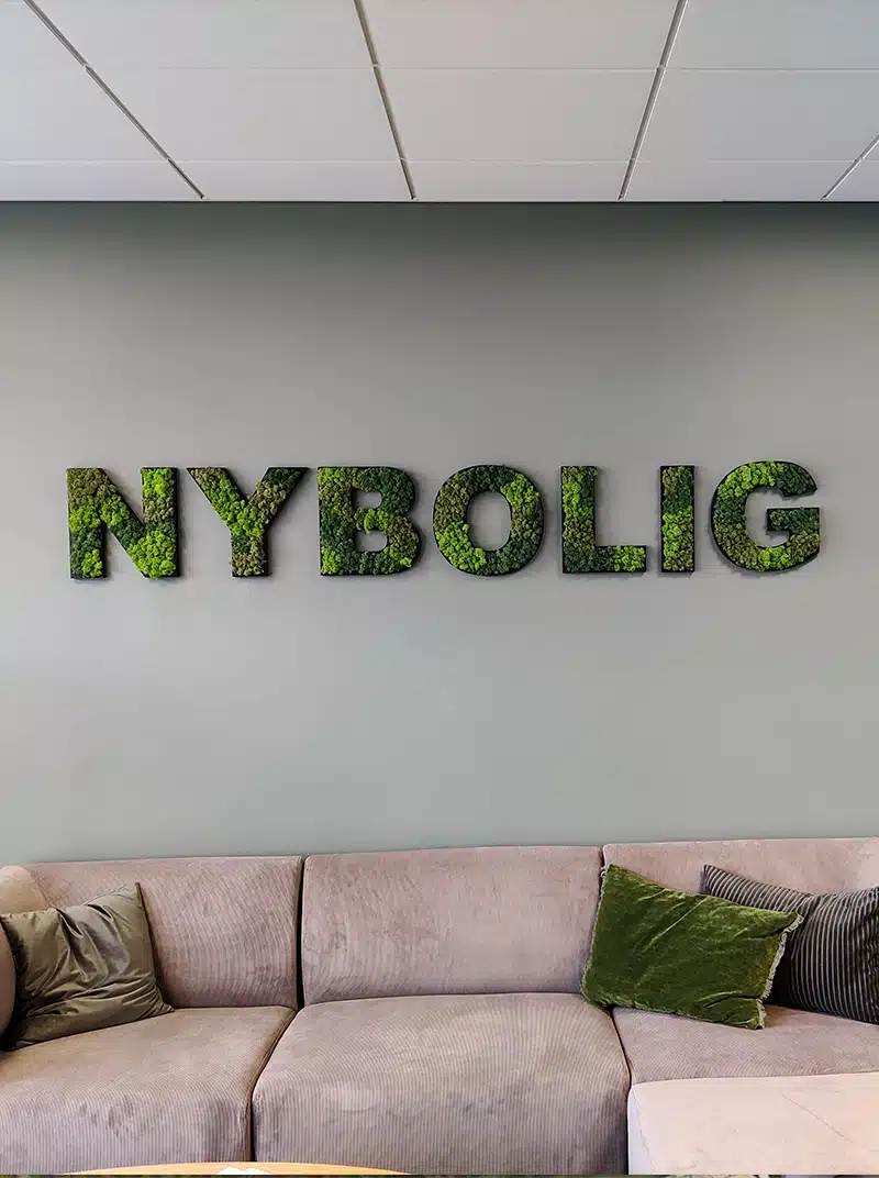Moss wall letters above beige couch with green pillows